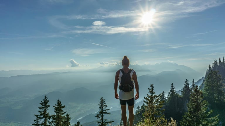 una mujer mirando al horizonte desde lo alto de una montaña