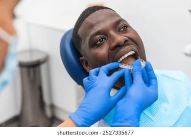 Orthodontie : un dentiste pose un aligneur en plastique transparent sur un homme.