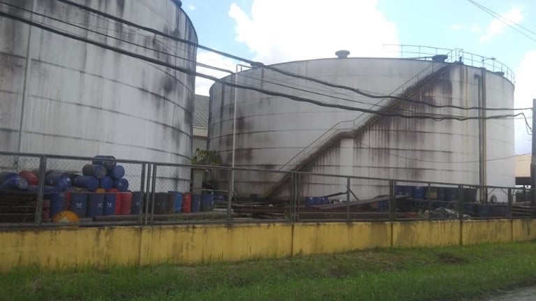 Industrial storage tanks and chemical barrels at an oil and gas refinery facility.