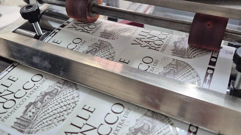 Industrial label applicator machine printing Valle San Rocco Prosecco wine bottle labels.
