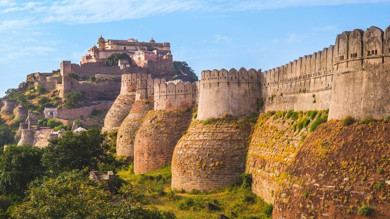 The massive fortified stone walls of Kumbhalgarh Fort in Rajasthan, India, under a blue sky.