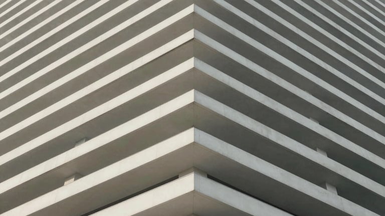 An abstract, architectural photography shot of clean white lines leading toward the corner of a building, symbolizing upward growth and structured progress.