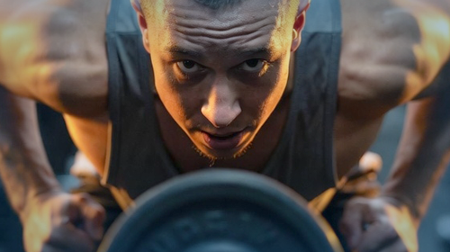 a man doing a push up barbell in a gym