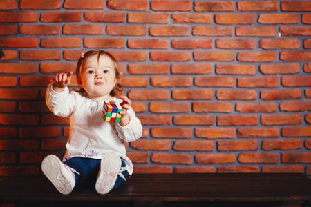 a little girl sitting on a table with a rubt toy