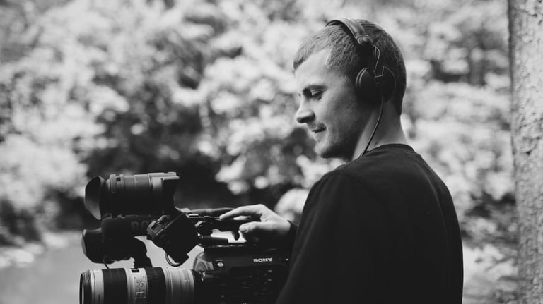 Mann mit Filmkamera im Wald - Aldan Kosnick mit Sony Kamera und Kopfhörern