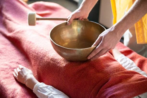 A Tibetan sound bowl resting on a person's body during a sound healing session
