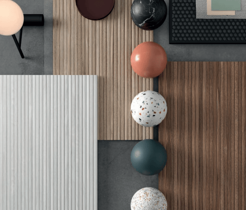 Flat lay of interior design samples featuring wood slat panels, marble spheres, and terrazzo textures.