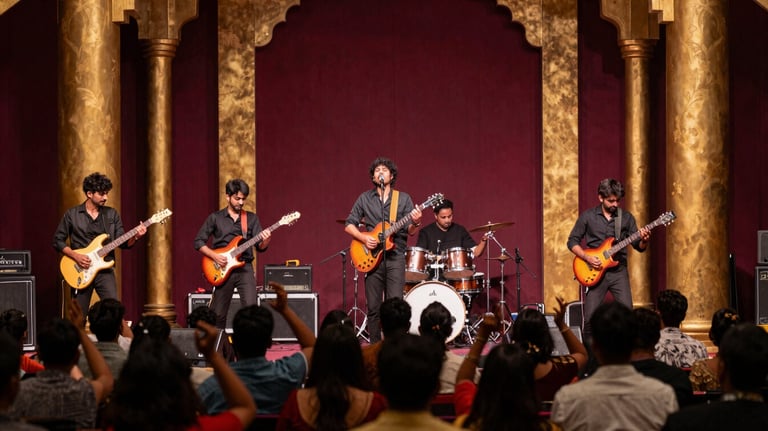 A high-energy live band performance on a modern stage with a South Asian / Indian audience dancing. Vibrant lights in antique gold and deep maroon.