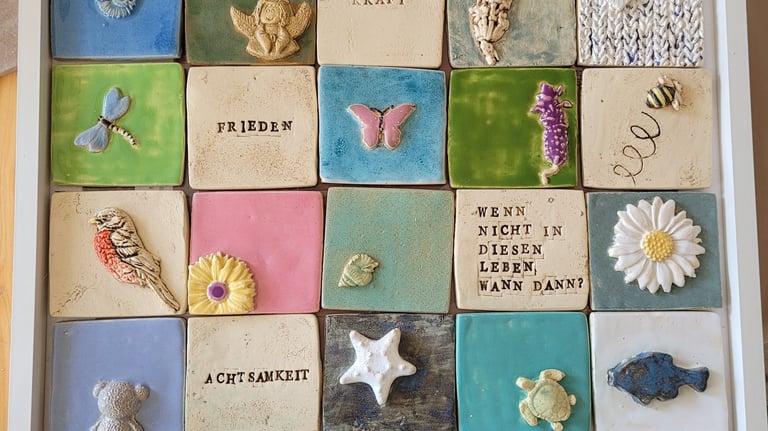 Handmade ceramic tiles with 3D animal and nature motifs in a white display frame.