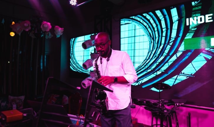 Professional saxophonist performing at London nightclub with vibrant stage lighting and neon backdro