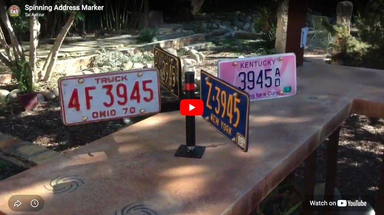 Weathervane-like object holding eight license plates all with numbers 3945 on them.