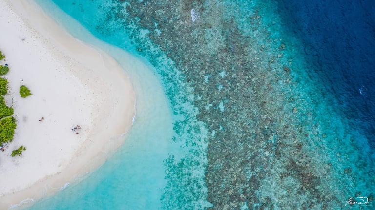 Aerial view of a white sand beach and coral reef in the turquoise ocean of the Maldives.