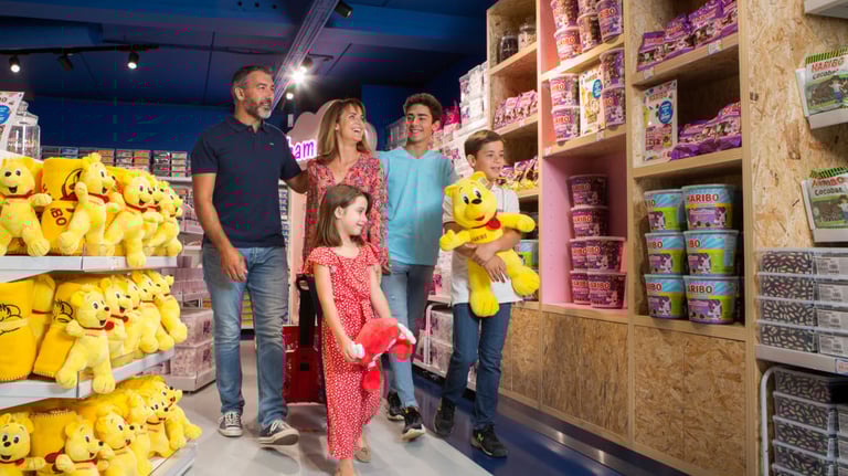 A happy family shopping for Haribo gummy bears and plush toys in a colorful candy store.