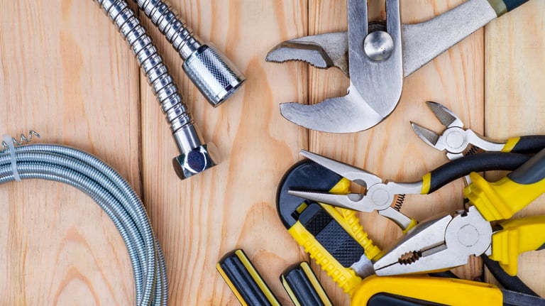 Various plumbing tools are laid out on a wooden table