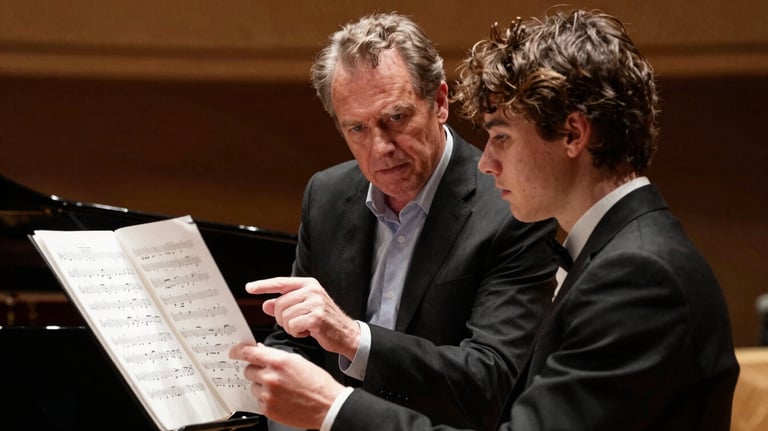 A mentor and a young musician discussing sheet music in a professional theater environment in the Pacific Northwest US. Timeless elegance and artistic focus.