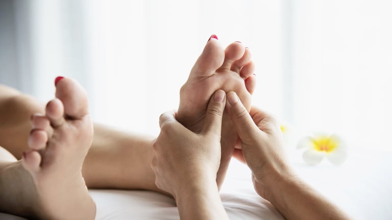 Massage therapist performing reflexology foot treatment on a client