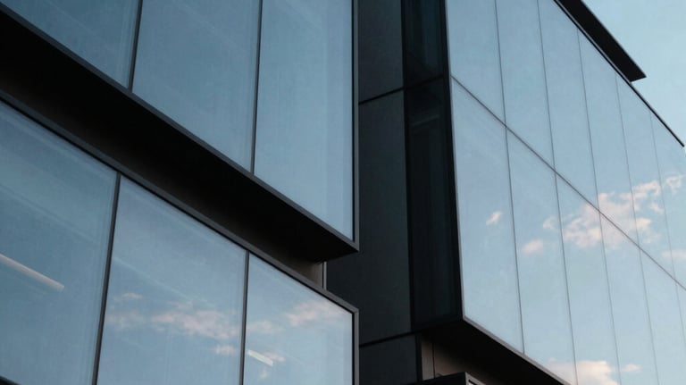 Abstract shot of modern architecture reflecting a sky blue sky, geometric shapes suggesting structure and scale.