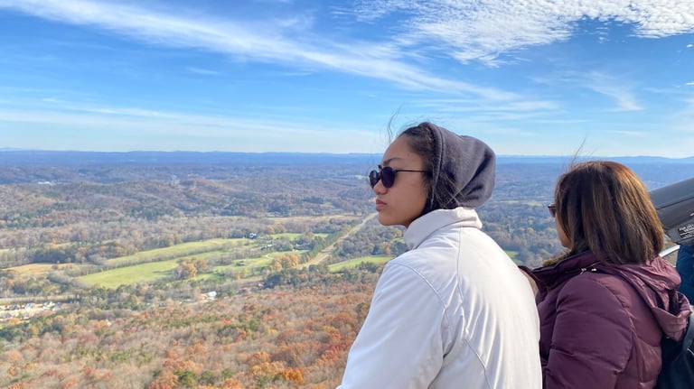 a woman in a white jacket and sunglasses on a mountain