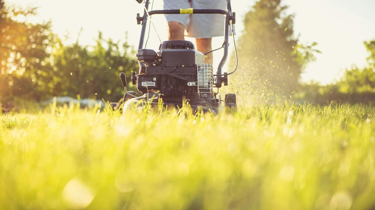 a man is standing in the grass with a lawn mower, person mowing the lawn