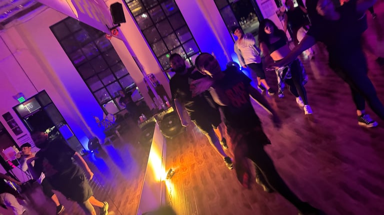 One dancer facing the camera and waving, while another dancer in the back follows.