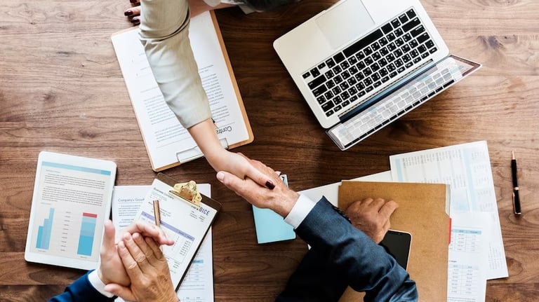 um grupo de pessoas apertando as mãos sobre papéis