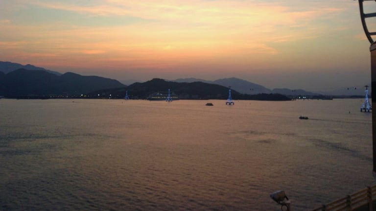 Navio chegando ao porto de Keelung pelo mar ao amanhecer, com vista da cidade e da costa