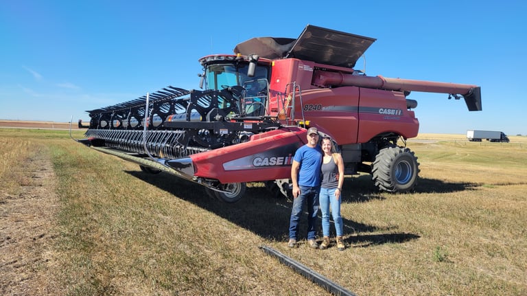 Ashley and her dad standing in front of a Case combine