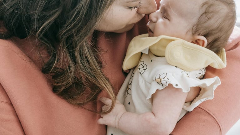 A mom holding her baby with their faces touching lovingly