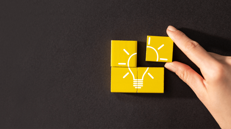 a person's hand holding a yellow light bulb on a black table
