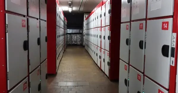 Narrow hallway lined with red and white secure storage lockers for public use.