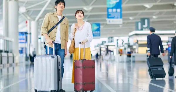 A happy couple with suitcases standing in a modern airport terminal for international travel.