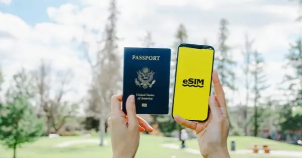 Hands holding a US passport and a smartphone displaying an eSIM logo for international travel connectivity.
