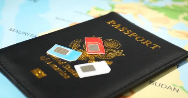 Three travel SIM cards resting on a US passport over a world map.