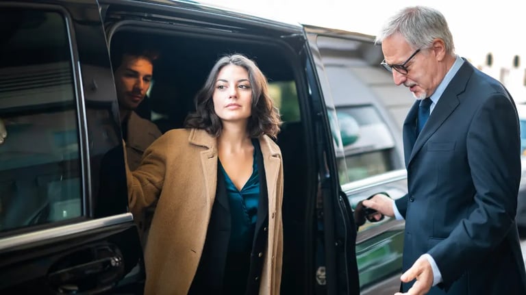 Professional chauffeur opening a black luxury car door for business travelers at an airport.