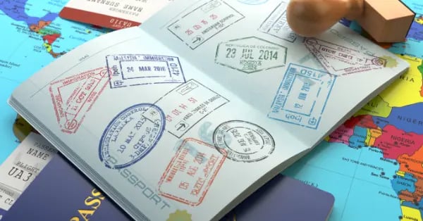 Open passport with international travel stamps on a world map with a wooden stamp.