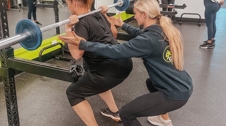 woman with personal training squatting in gym