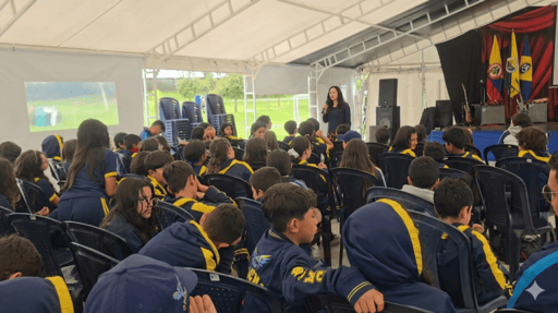 Una mujer hace una presentación a los estudiantes, que visten uniforme escolar