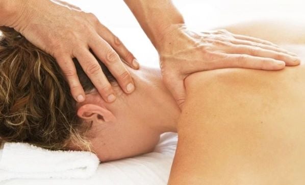 A woman face down getting a neck and shoulder massage.