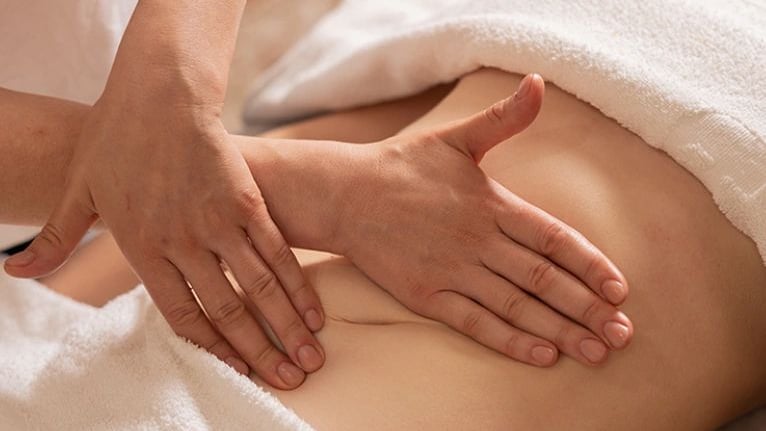 Hands massaging someone's stomach.