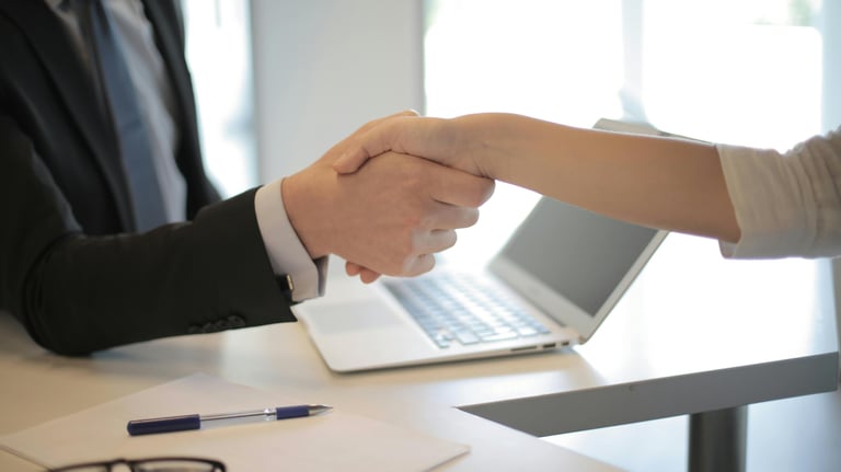 a man and woman shaking hands over a laptop