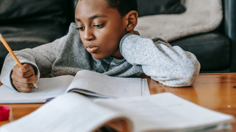 a young boy is sitting at a table with a pencil and pencil