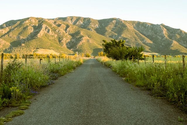 a road with a fenced in area with mountains in the background