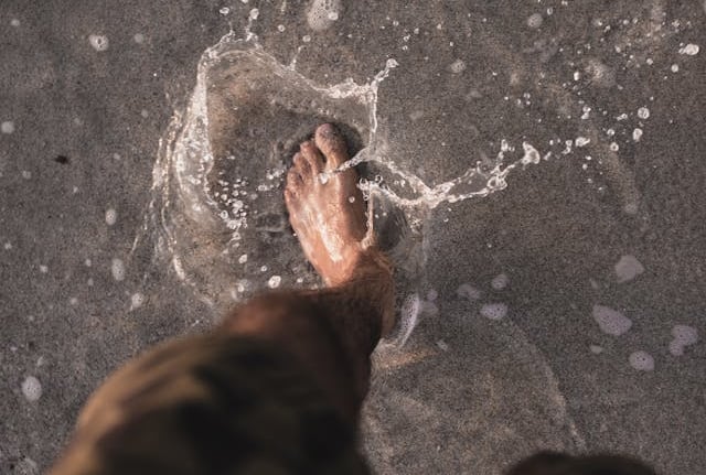 a person standing in the water with their feet in the water