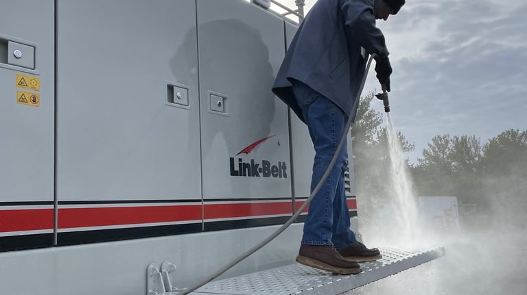 a man in a blue jacket is using a hose to clean a boat