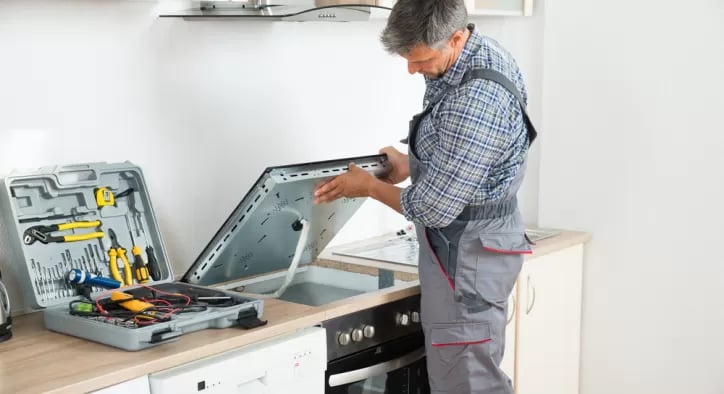 a technician installing a cooktop onto countertop in a kitchen