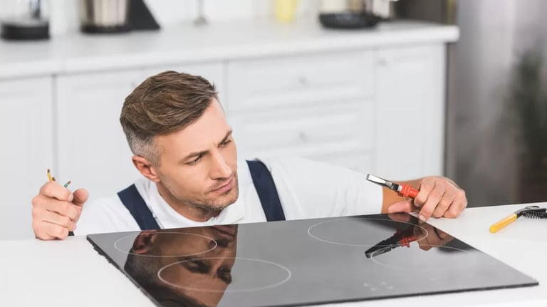 a man holding a plier while looking at a glass cooktop