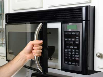a person opening a black otr microwave door