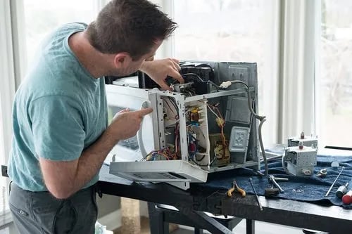 a person repairing a microwave on a table