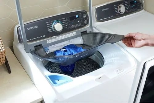 samsung washer and dryer shown by a person holds the top basket