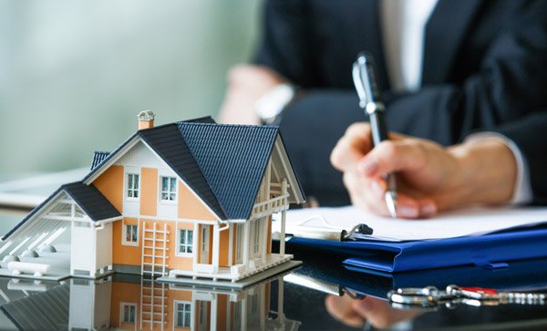 a person sitting at a desk with a pen and house on the table